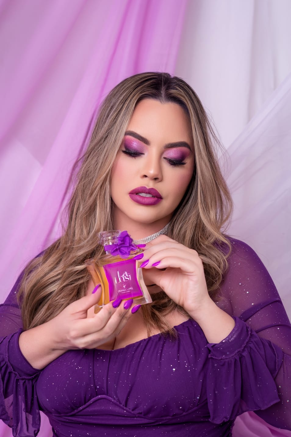 Mulher segurando o frasco La Lust em cenário roxo